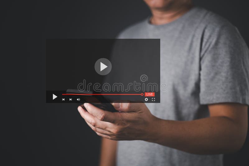 一名男子拿着一部智能手机，屏幕上叠加了数字直播界面。屏幕上显示一个播放按钮和一个进度条 免版税图库摄影