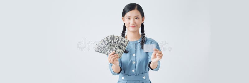 一张幸福的年轻女子孤身站立，手中拿着钱和信用卡 免版税库存图片