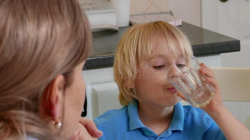 一点逗人喜爱的孩子男孩喝从玻璃杯子的汁液