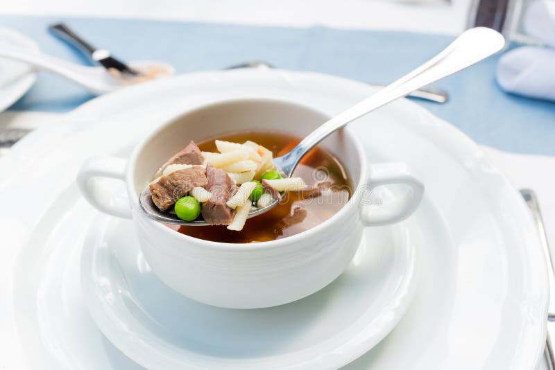 A bowl of delicious beef and barley soup with carrots, tomato, potato, celery, and peas. A bowl of delicious beef and barley soup with carrots, tomato, potato, celery, and peas