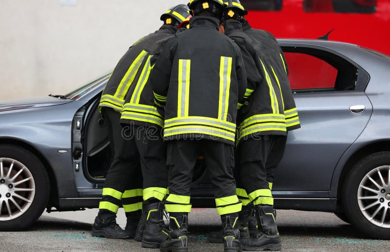 一群消防员从事故车辆中救出伤员，此前发生了一起交通事故 免版税库存图片