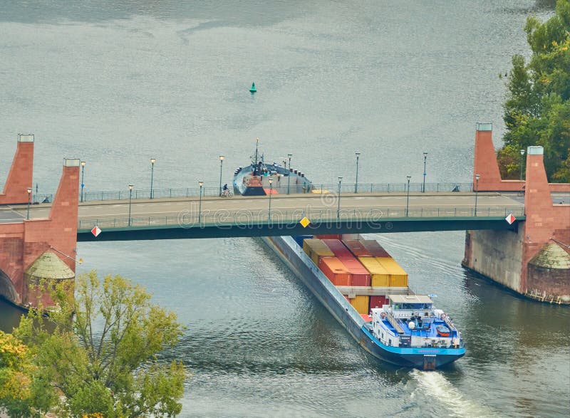 Frankfurt, Germany, October 2., 2019: A ship loaded with containers passes under a bridge that crosses the Main River. Frankfurt, Germany, October 2., 2019: A ship loaded with containers passes under a bridge that crosses the Main River