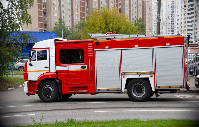 A fire truck is driving an emergency call on a road in the city. side view. A fire truck is driving an emergency call on a road in the city. side view.