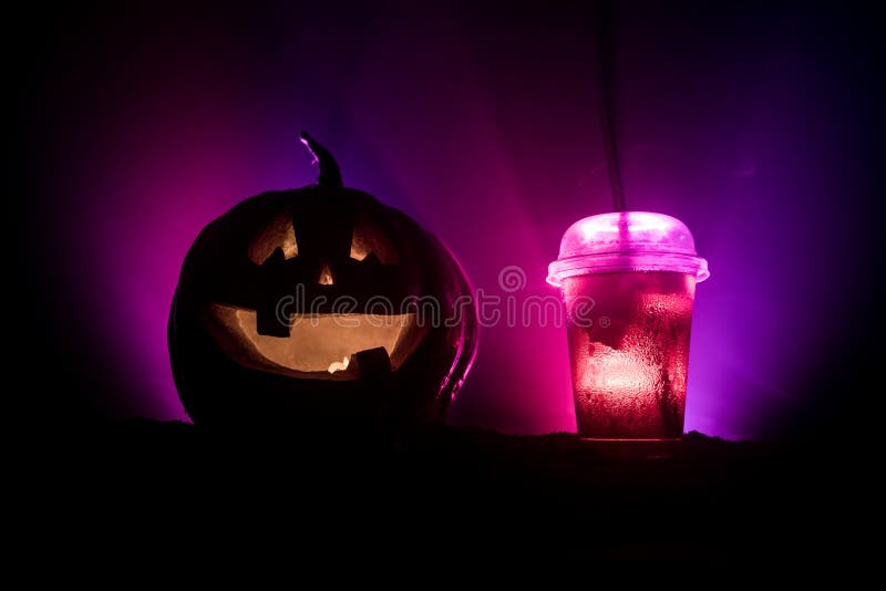 Halloween pumpkin orange cocktails. Festive drink. Halloween party. Funny Pumpkin with a glowing cocktail glass on a dark toned foggy background. Selective focus. Halloween pumpkin orange cocktails. Festive drink. Halloween party. Funny Pumpkin with a glowing cocktail glass on a dark toned foggy background. Selective focus