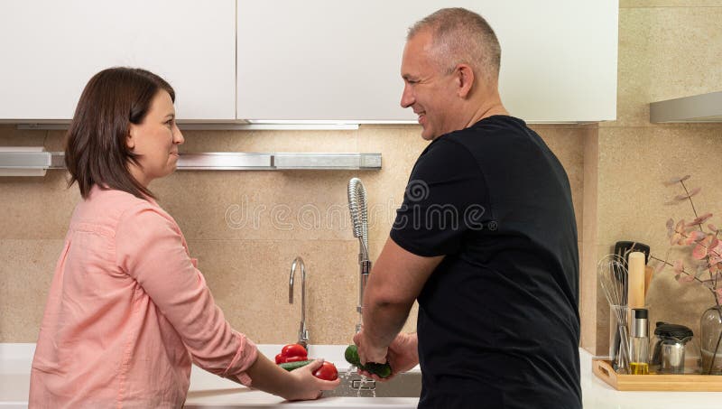 Husband helps his wife in the kitchen with cooking vegetables. Husband helps his wife in the kitchen with cooking vegetables.