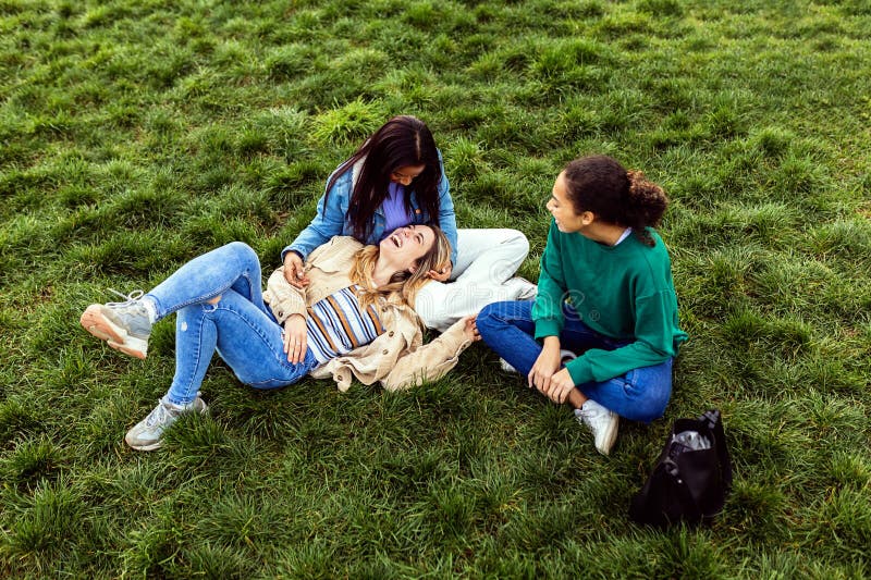 三个不同年龄的女孩在城市公园里一起放松. 免版税库存照片