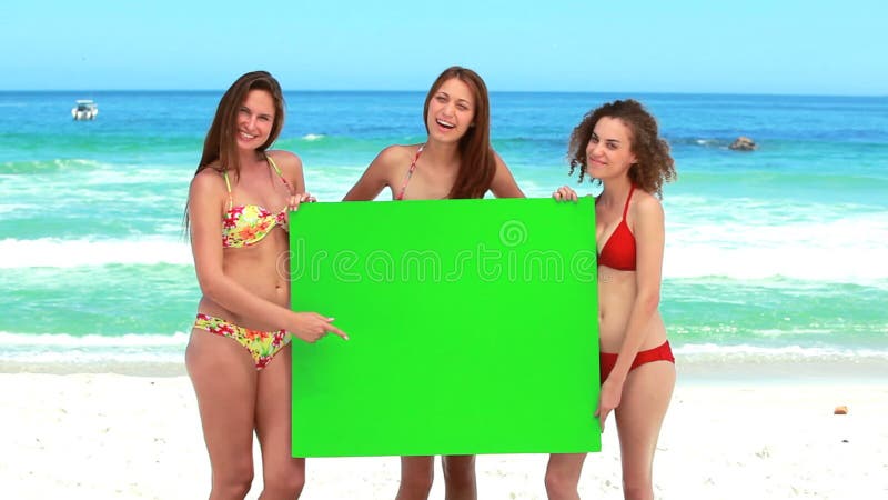 三个女孩拿着一个绿色屏幕