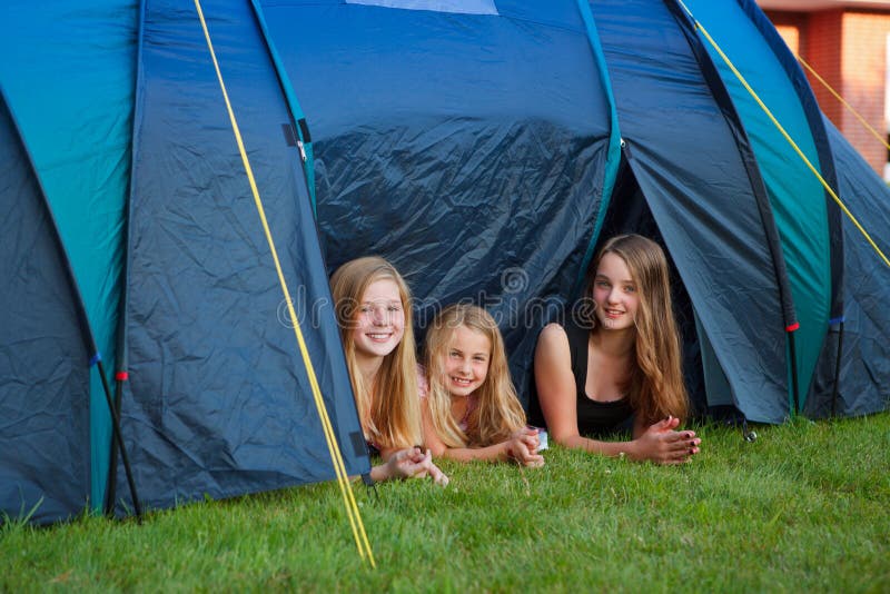 Three girls looking out of their camping tent. Three girls looking out of their camping tent