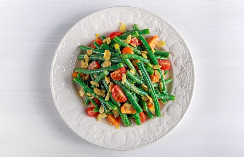 与bruschettas、红色、黄色蕃茄和雪片杏仁的青豆沙拉在白色板材 免版税库存图片 与bruschettas、红色、黄色蕃茄和雪片杏仁的青豆沙拉在白色板材 免版税库存图片