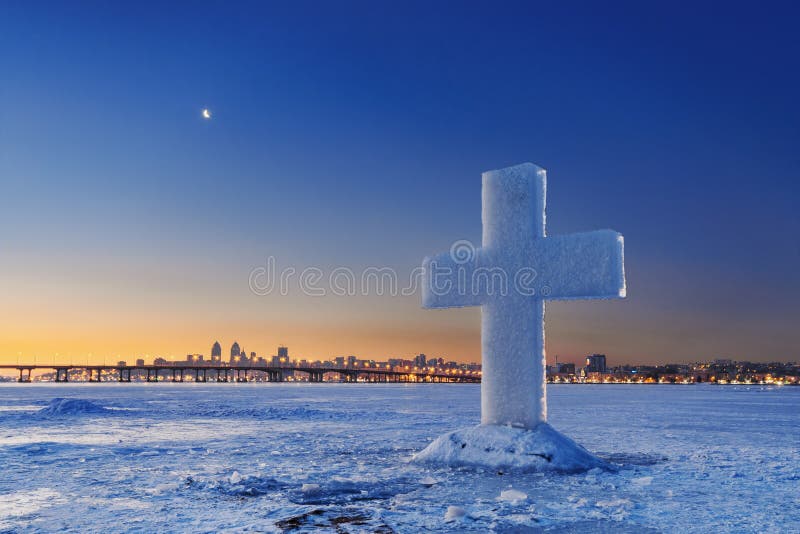 与冰十字架的美好的冬天风景在黄昏的冻河