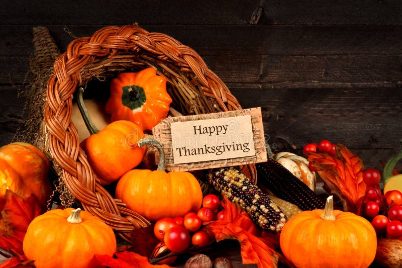 Harvest cornucopia close up with Happy Thanksgiving gift tag on dark wood background. Harvest cornucopia close up with Happy Thanksgiving gift tag on dark wood background
