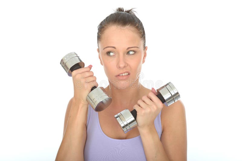 A DSLR royalty free image, an unmotivated healthy young woman, looking fed up or unimpressed, holding two or 2 dumb bell weights, pulling a silly facial expression, with hair pulled back of face, wearing lilac or purple vest top, shot against a white background. A DSLR royalty free image, an unmotivated healthy young woman, looking fed up or unimpressed, holding two or 2 dumb bell weights, pulling a silly facial expression, with hair pulled back of face, wearing lilac or purple vest top, shot against a white background.