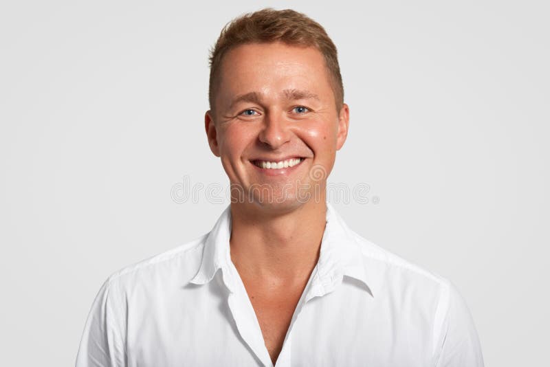 与正面表示的快乐的满意的男性,展示白色牙,在好心情在成功的会议以后,在白色穿戴了 免版税库存照片 与正面表示的快乐的满意的男性,展示白色牙,在好心情在成功的会议以后,在白色穿戴了 免版税库存照片