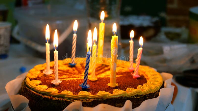 与灼烧的蜡烛的美丽的可口生日蛋糕在厨房用桌上