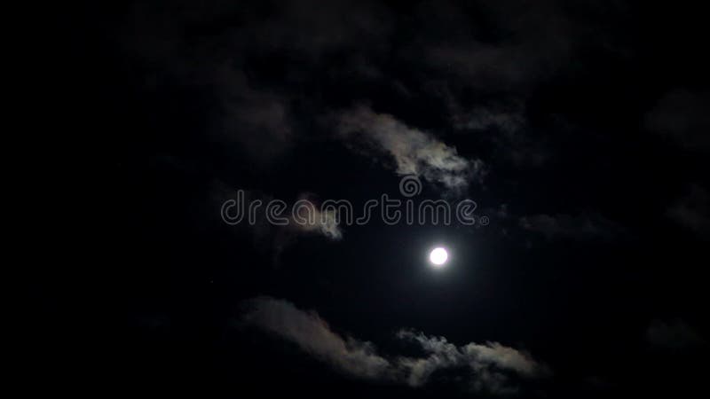 与羊毛状的云彩的被月光照亮夜通过深蓝天空