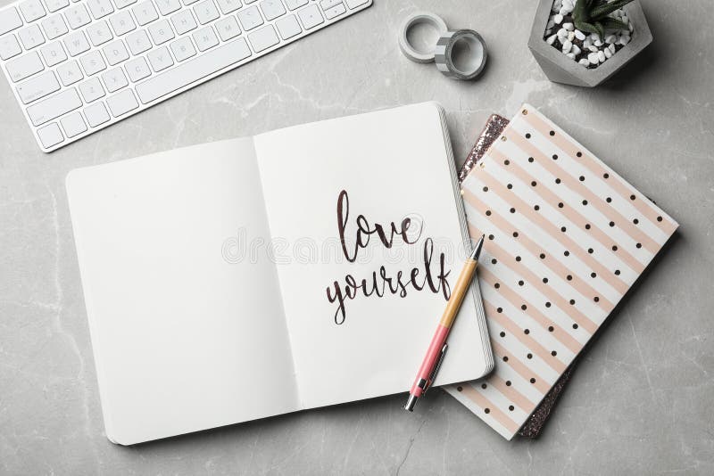 Flat lay composition with words LOVE YOURSELF written in notebook on grey table. Flat lay composition with words LOVE YOURSELF written in notebook on grey table