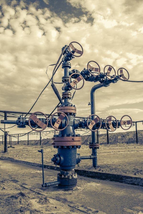 Wellhead with valve armature. Oil and gas industry concept. Industrial site background. Toned. Wellhead with valve armature. Oil and gas industry concept. Industrial site background. Toned.