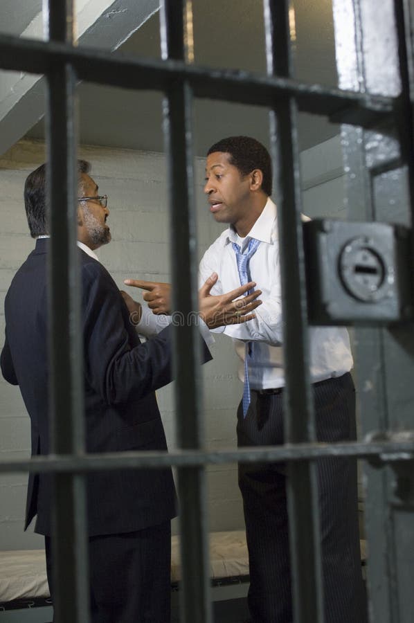 Two businessmen arguing behind bars in prison. Two businessmen arguing behind bars in prison