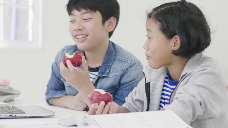 两个孩子吃着苹果 并且做家庭作业