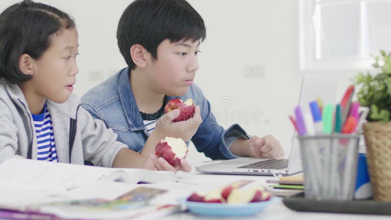 两个孩子吃着苹果 并且做家庭作业