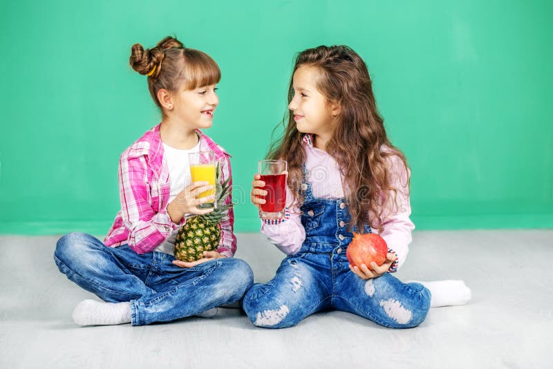 两个孩子是谈和喝汁液 有pineappl的女孩 免版税库存图片 两个孩子是谈和喝汁液 有pineappl的女孩 免版税库存图片