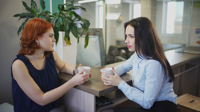 两名妇女咖啡讲话在办公室里面的饮料破坏