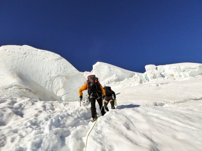 两爬山者朝向对在陡峭的冰川的一个高高山峰顶