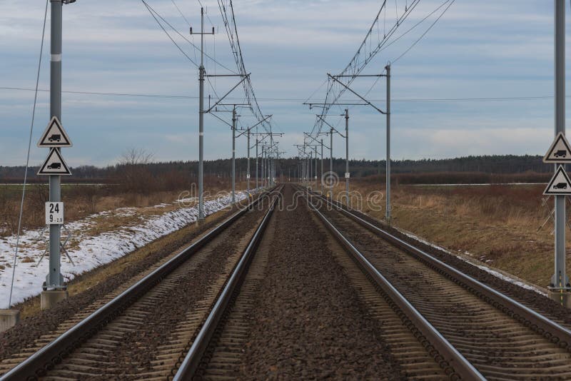 A view of the two-track, electrified railway track.
Winter, cloudy day. The ground is covered with sheets of snow. A two-track, electrified railway track. You can see the elements of electric traction in the form of metal poles, electric cables. Straight rails leading to the horizon. On the embankment you can see patches of a thin layer of snow. There are fields and meadows on both sides of the tracks. A view of the two-track, electrified railway track.
Winter, cloudy day. The ground is covered with sheets of snow. A two-track, electrified railway track. You can see the elements of electric traction in the form of metal poles, electric cables. Straight rails leading to the horizon. On the embankment you can see patches of a thin layer of snow. There are fields and meadows on both sides of the tracks.