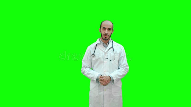 严肃的男性医生谈话与在一个绿色屏幕上的照相机，色度钥匙
