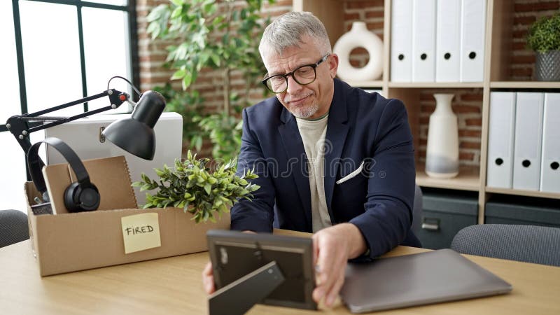 Middle age grey-haired man business worker dismissed putting things on cardboard box at office. Middle age grey-haired man business worker dismissed putting things on cardboard box at office