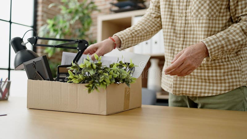 Middle age man business worker dismissed putting document on cardboard box at office. Middle age man business worker dismissed putting document on cardboard box at office