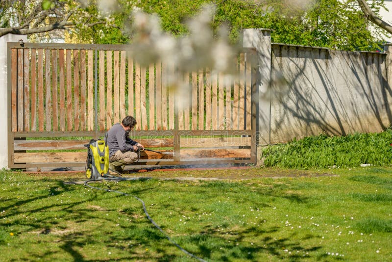 中年男子用电动洗衣机清理木门 用于DIY修复花园闸门的高压水压清洗机