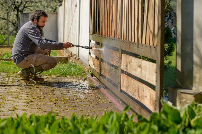 中年男子用电动洗衣机清理木门 用于DIY修复花园闸门的高压水压清洗机
