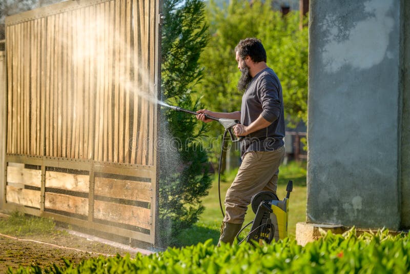 中年男子用电动洗衣机清理木门 用于DIY修复花园闸门的高压水清器