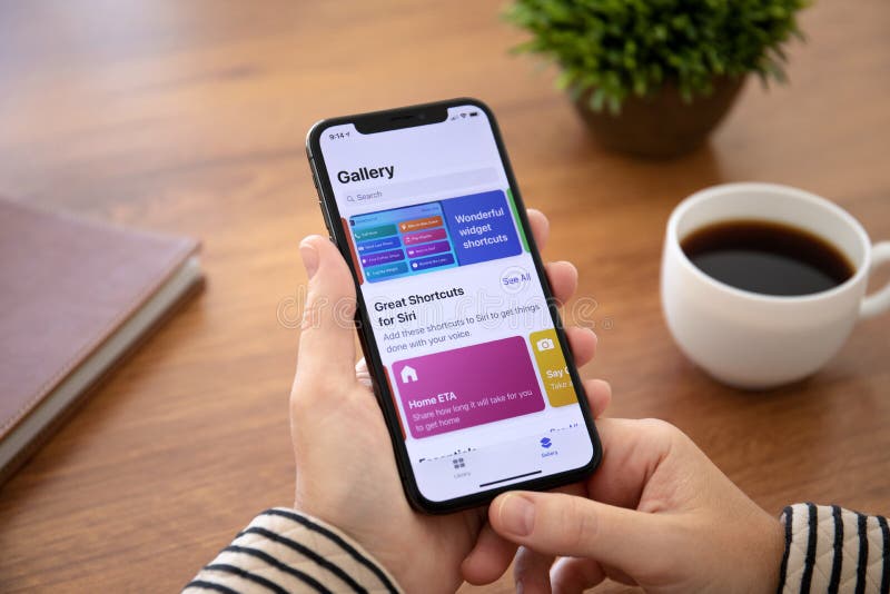 Alushta, Russia - September 26, 2018: Woman hand holding iPhone X with home screen Shortcuts app. iPhone 10 was created and developed by the Apple inc. Alushta, Russia - September 26, 2018: Woman hand holding iPhone X with home screen Shortcuts app. iPhone 10 was created and developed by the Apple inc.