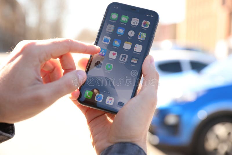 MYKOLAIV, UKRAINE - MARCH 16, 2020: Man holding iPhone 11 with home screen outdoors, closeup. MYKOLAIV, UKRAINE - MARCH 16, 2020: Man holding iPhone 11 with home screen outdoors, closeup