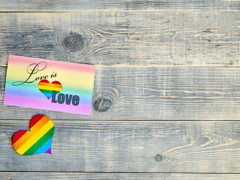书面爱的卡片是爱有彩虹背景和心脏与LGBT旗子谎言在一浅兰织地不很细木 库存照片 书面爱的卡片是爱有彩虹背景和心脏与LGBT旗子谎言在一浅兰织地不很细木 库存照片