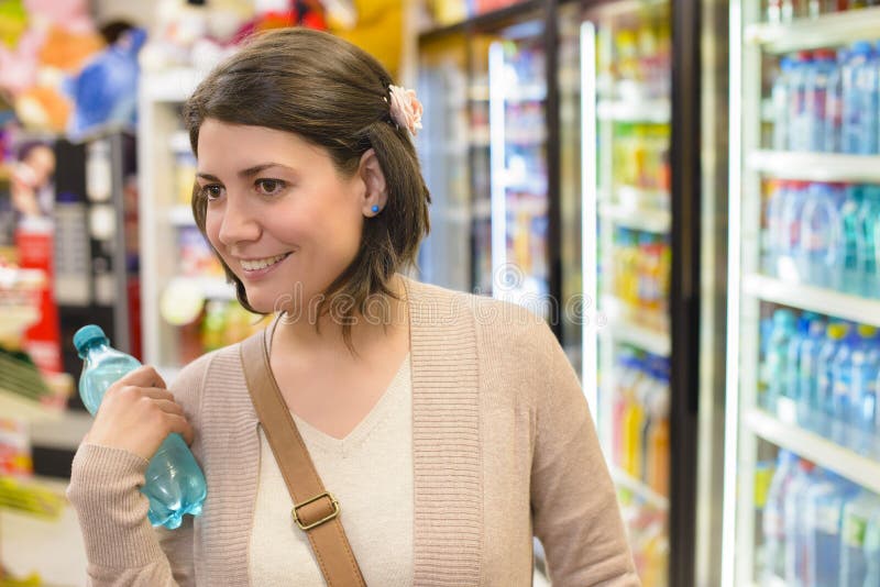 Young woman buying a bottle of water from a store. Young woman buying a bottle of water from a store