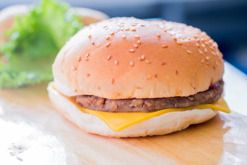 Closeup of a cheese burger on a wooden plate. Closeup of a cheese burger on a wooden plate