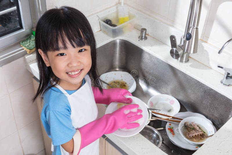 亚洲中国小女孩洗涤的盘在厨房里 库存图片