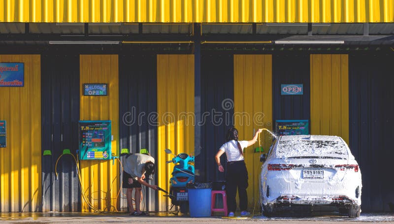 亚洲人在自助洗车小商店24小时概念店洗车和摩托车 免版税库存照片