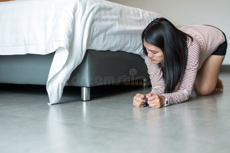 亚洲女性倾向和搜寻某事在床失去的事下在卧室 免版税库存图片 亚洲女性倾向和搜寻某事在床失去的事下在卧室 免版税库存图片