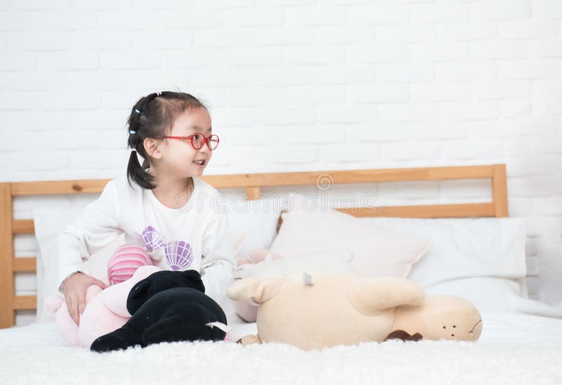 亚洲小可爱女孩坐在床上,里面摆着许多可爱的娃娃 图库摄影 亚洲小可爱女孩坐在床上,里面摆着许多可爱的娃娃 图库摄影