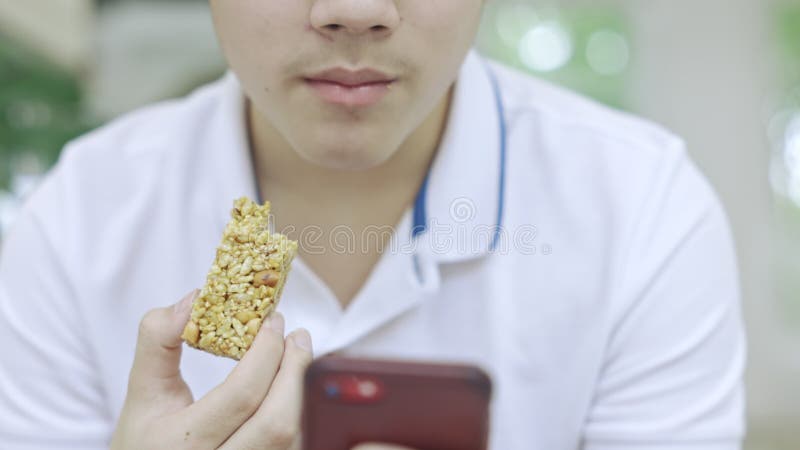 亚洲少年男孩一边吃零食一边用手机