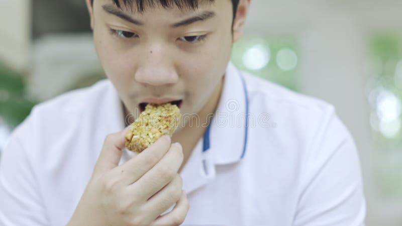 亚洲少年男孩一边吃零食一边用手机