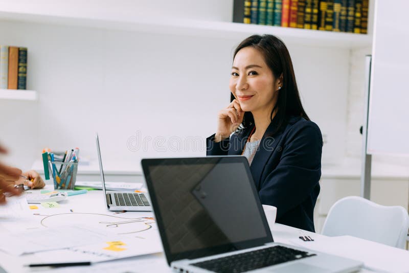 亚洲成熟的女商人坐在会议上微笑着，看着镜头