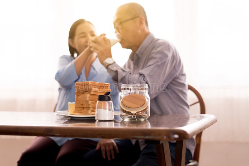 亚洲老人夫妻一起喝牛奶早餐的模糊现象 库存照片 亚洲老人夫妻一起喝牛奶早餐的模糊现象 库存照片