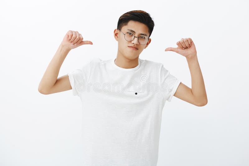 亚裔人是赞成感觉骄傲和自信胜利,是指向他自己的优胜者与掀动头的拇指 免版税图库摄影 亚裔人是赞成感觉骄傲和自信胜利,是指向他自己的优胜者与掀动头的拇指 免版税图库摄影
