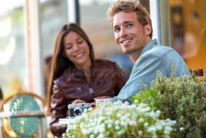 享受坐的年轻都市人在与朋友的餐馆桌上在城市 应征欧洲旅行夫妇假期 偶然生活方式