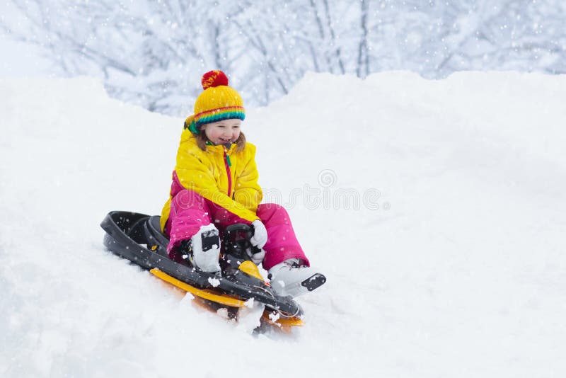 享受雪橇乘驾的小女孩 儿童sledding 乘坐爬犁的小孩孩子 户外儿童游戏在雪 在的孩子雪撬 免版税库存照片 享受雪橇乘驾的小女孩 儿童sledding 乘坐爬犁的小孩孩子 户外儿童游戏在雪 在的孩子雪撬 免版税库存照片
